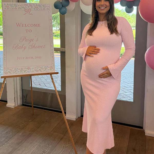 Roze zwangerschaps maxi jurk met zeemeerminmodel en flare mouwen, ideaal voor een babyshower.