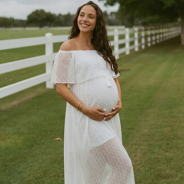 Witte zwangerschaps maxi jurk met stippenprint, off-shoulder en zijsplit, ideaal voor een fotoshoot.