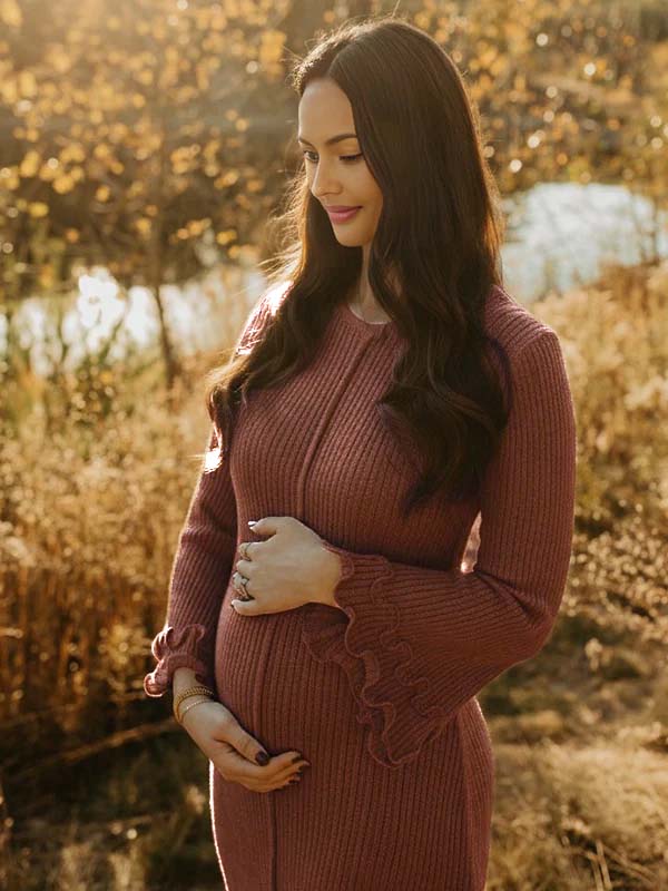 Bruine ribgebreide zwangerschapsjurk met ruchesmanchetten, ideaal voor een herfstfotoshoot.
