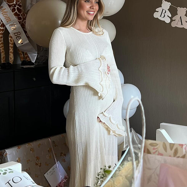 Witte zwangerschaps maxi jurk met open rug, golvende rand en koorddetails voor babyshower.