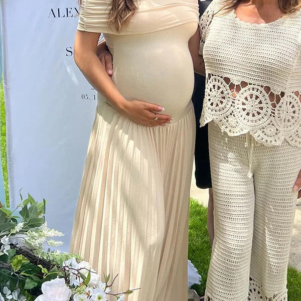 Abrikooskleurige zwangerschaps maxi jurk met off-shoulder en plooien, ideaal voor een babyshower.