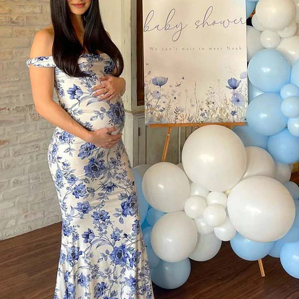 Blauwe zwangerschaps maxi jurk met bloemenprint en off-shoulder, ideaal voor een babyshower.