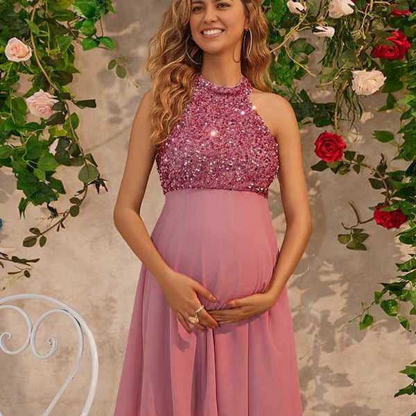 Roze korte zwangerschaps cocktailjurk met pailletten, rugloos design en halternek voor feest.