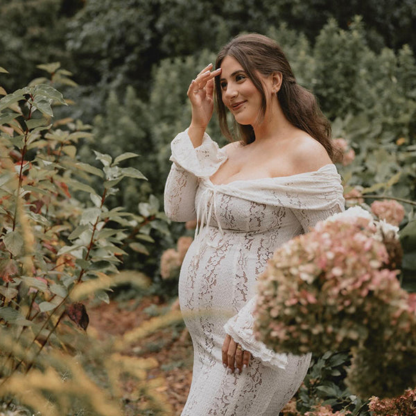 Witte kanten zwangerschaps maxi jurk met off-shoulder, strikdetail en zeemeerminmodel, ideaal voor fotoshoots.