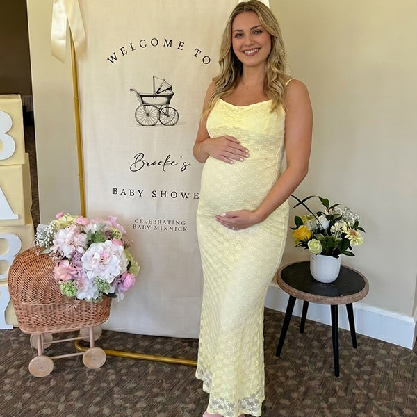 Gele zwangerschaps maxi jurk met bloemenprint, spaghettibandjes en zeemeermin bodycon silhouet.