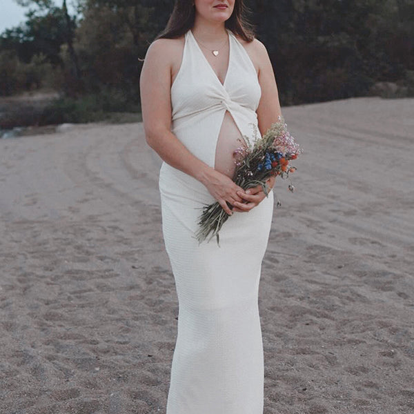 Witte zwangerschaps maxi jurk met 2-in-1 design en halternek, ideaal voor fotoshoot.