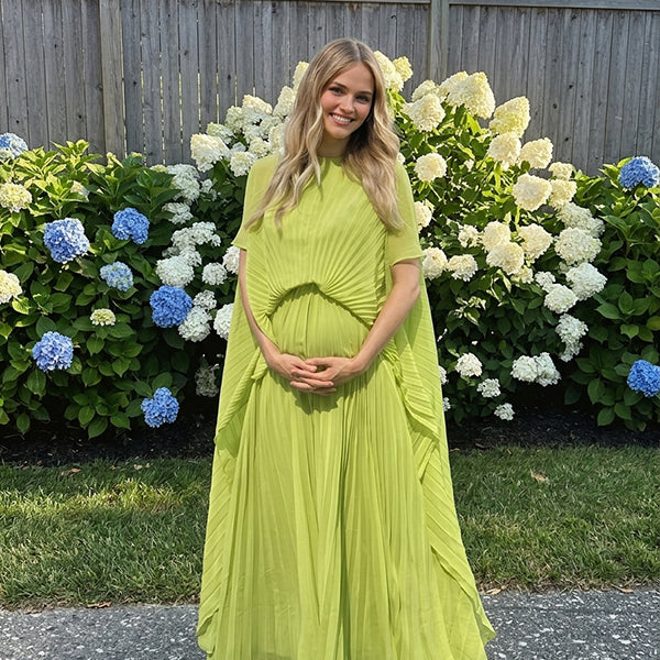 Groene zwangerschaps maxi jurk met plooien, open rug en strikdetail, ideaal voor feest.
