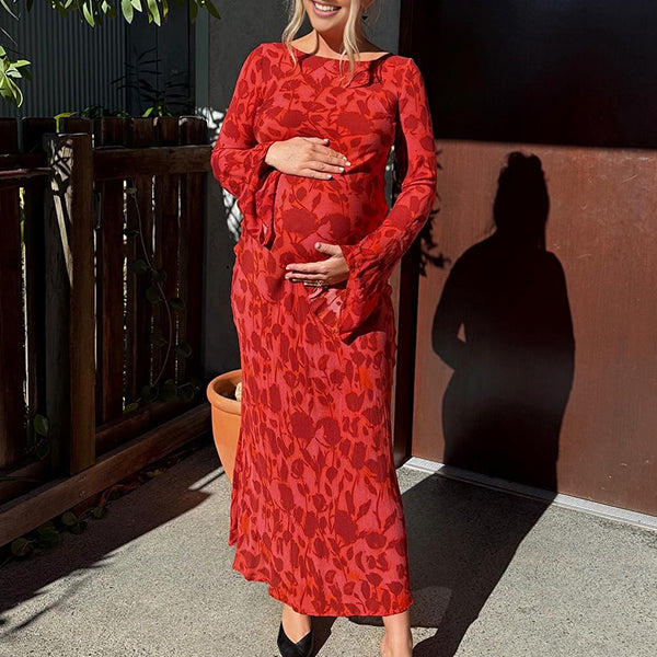 Rode zwangerschaps maxi avondjurk met bloemenprint, draperie en flare mouwen, ideaal voor ceremonie.