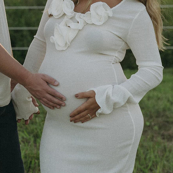Witte zwangerschaps maxi jurk met ruches, zijsplit en bodycon pasvorm, ideaal voor een fotoshoot.