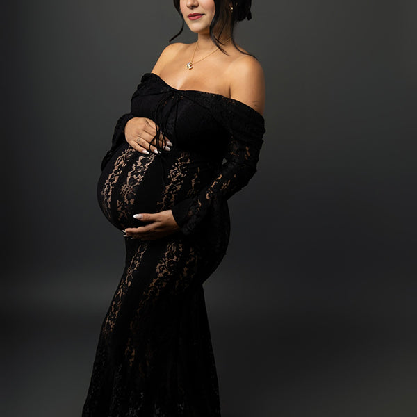 Zwarte zwangerschaps maxi jurk met off-shoulder design, kant, ruches en zeemeerminmodel, ideaal voor fotoshoot.