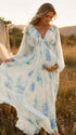 Blauwe zwangerschaps maxi jurk met bloemenprint, ruches en fladderende details voor fotoshoot.