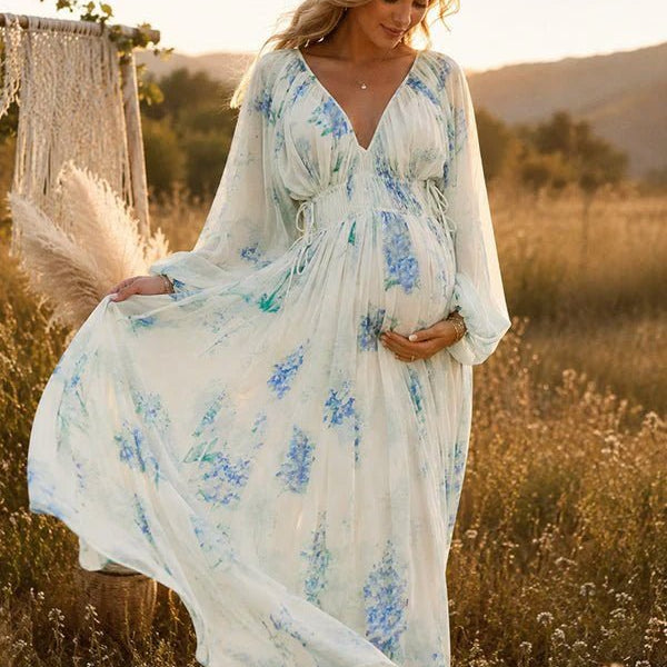 Blauwe zwangerschaps maxi jurk met bloemenprint, ruches en fladderende details voor fotoshoot.