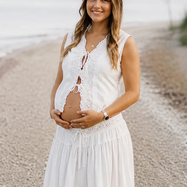 Witte boho tweedelige zwangerschapsjurk met vetersluiting, ideaal voor fotoshoots.